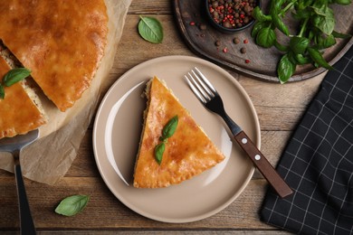 Photo of Delicious pie with meat and basil on wooden table, flat lay