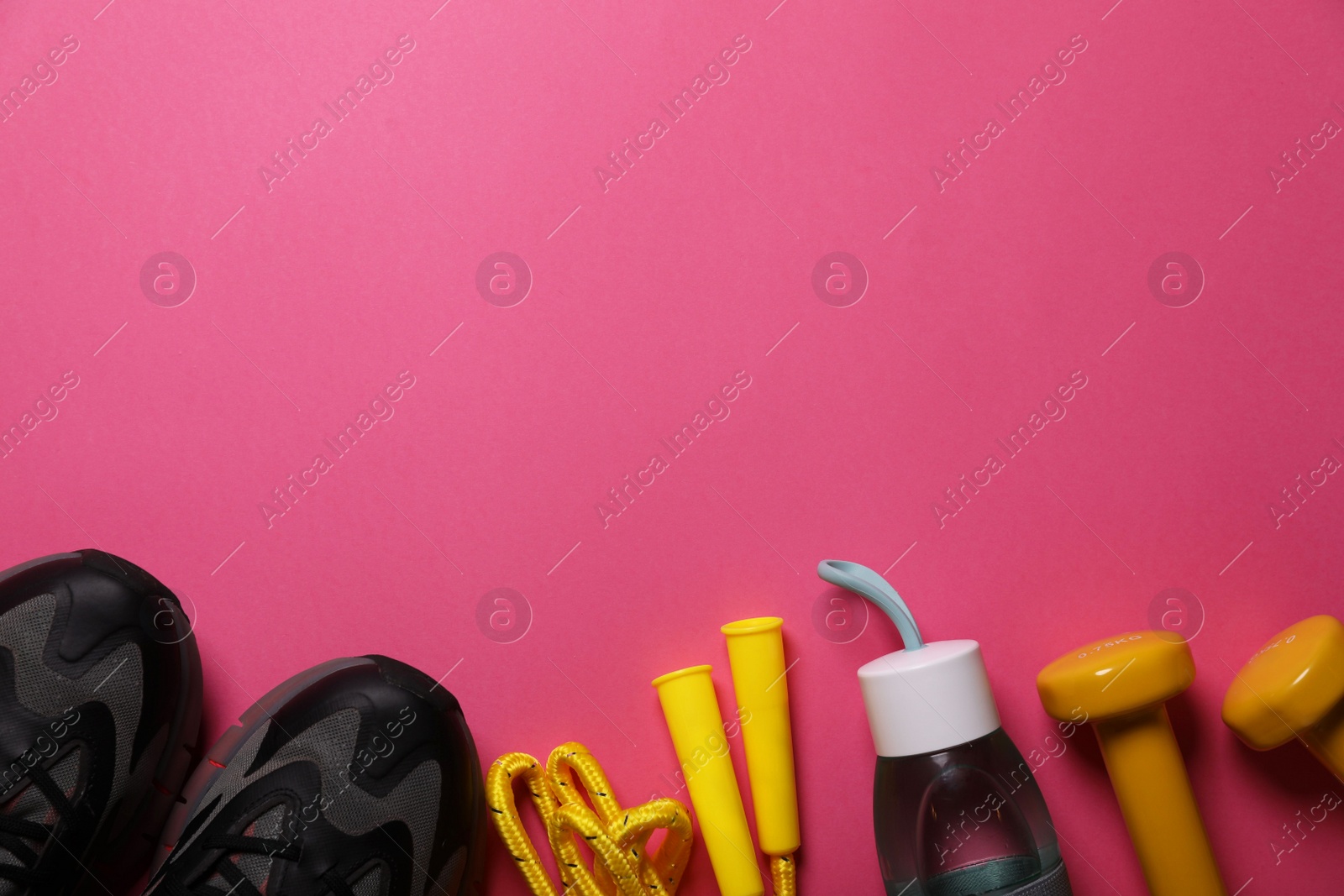 Photo of Sneakers, dumbbells and bottle of water on pink background, flat lay with space for text. Morning exercise