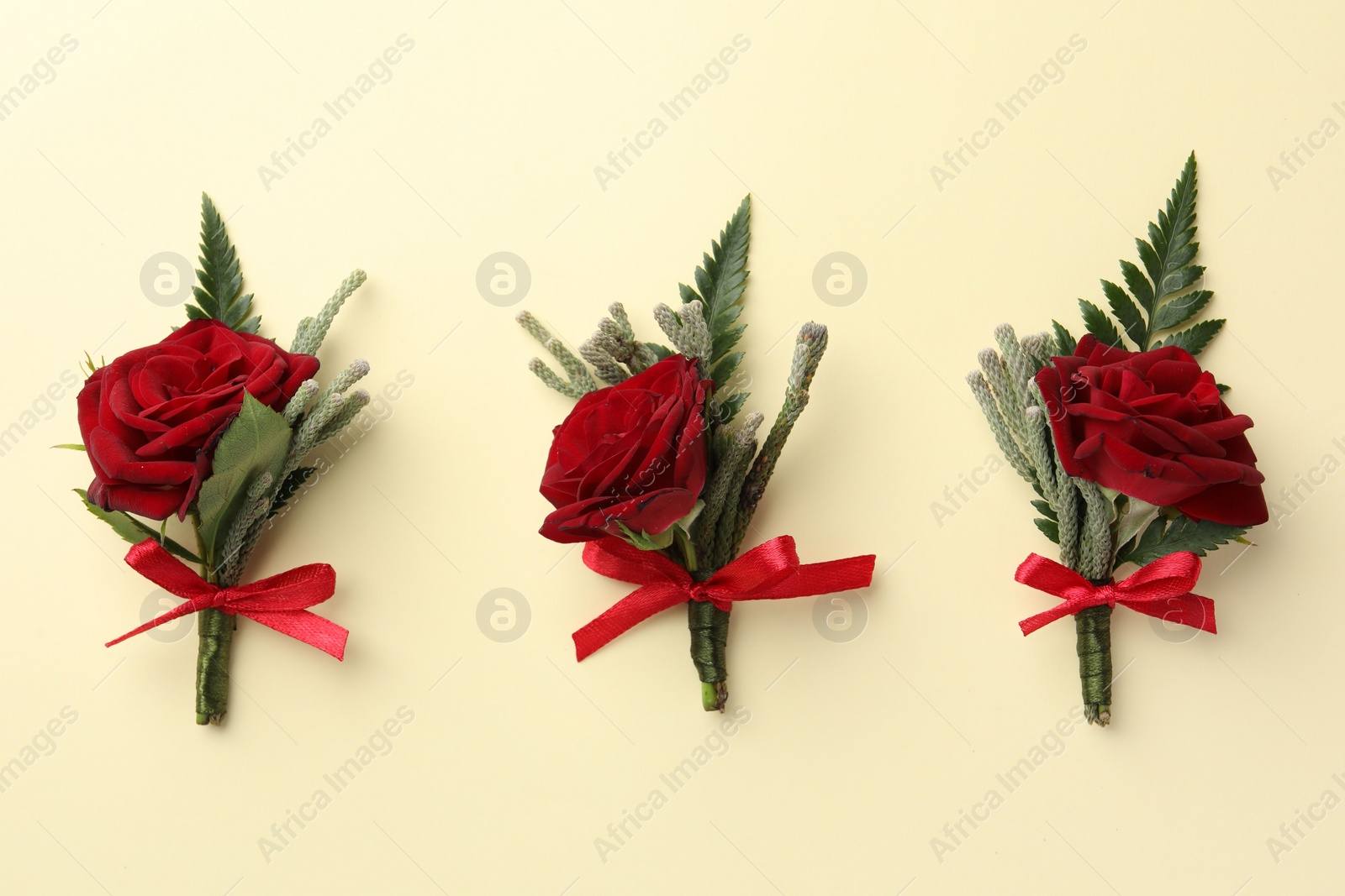 Photo of Many stylish red boutonnieres on beige background, flat lay