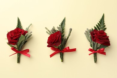 Photo of Many stylish red boutonnieres on beige background, flat lay