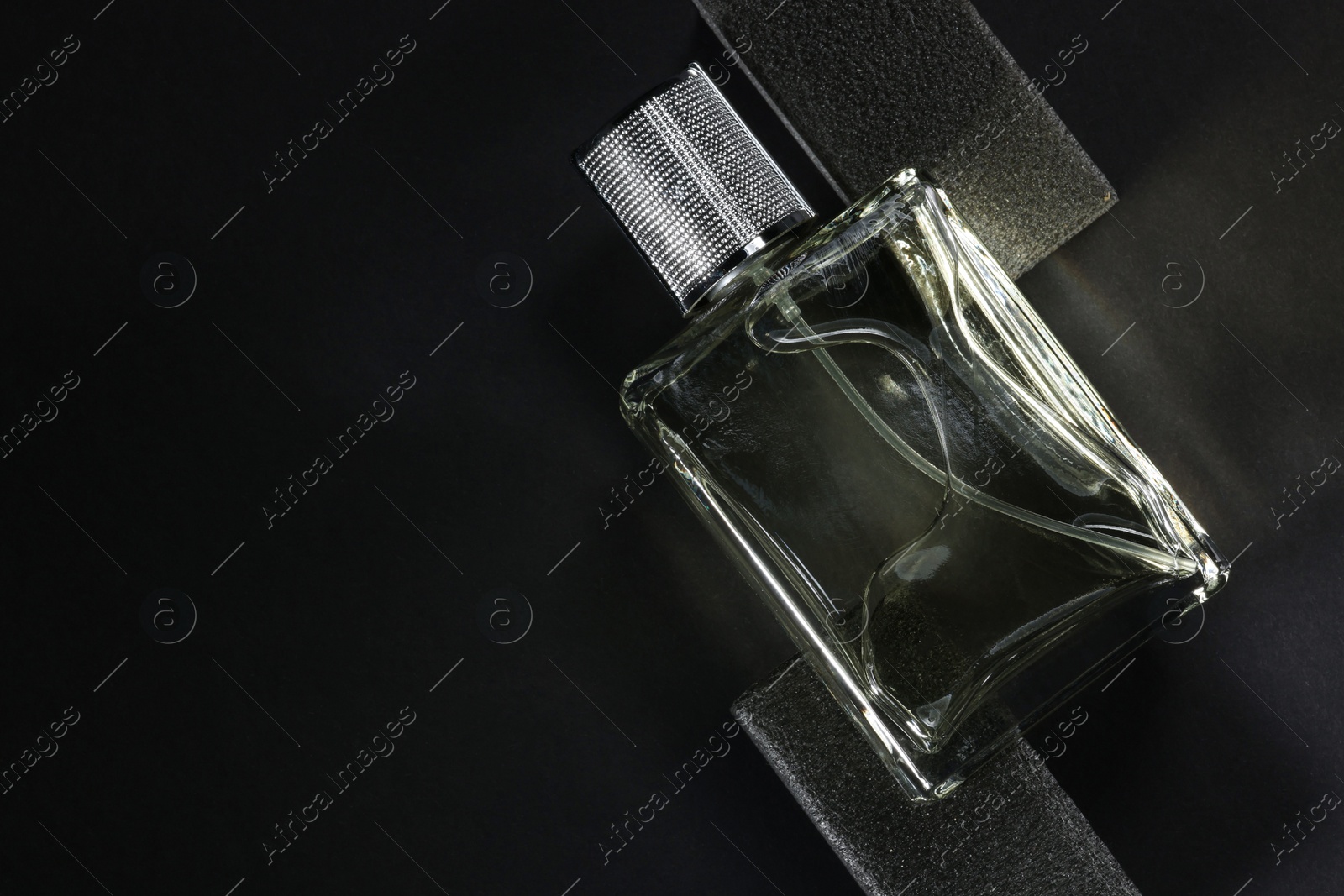 Photo of Stylish presentation of luxury men`s perfume in bottle on black background, top view. Space for text