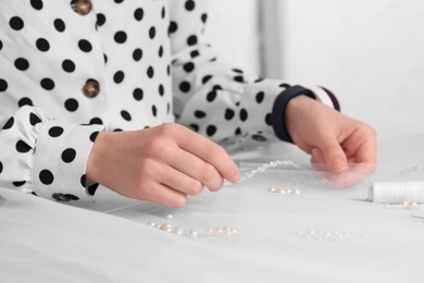 Photo of Dressmaker with sewing accessories at white table in atelier, closeup