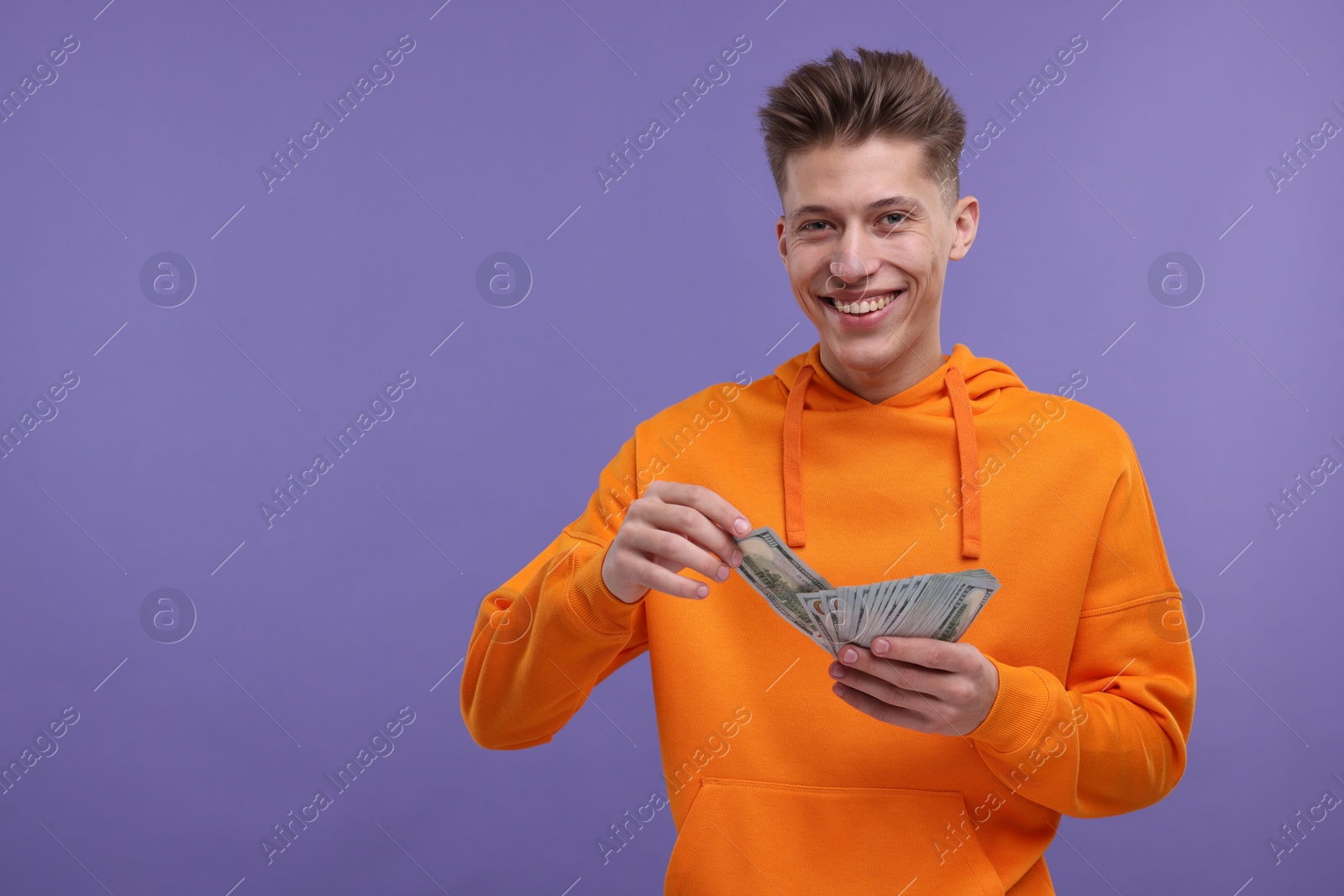 Photo of Happy man with money on purple background. Space for text