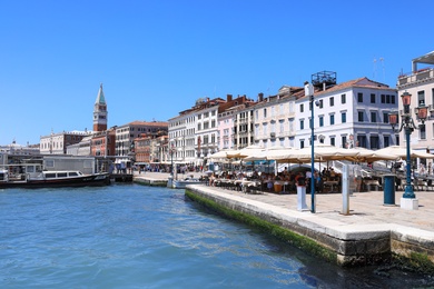 Photo of VENICE, ITALY - JUNE 13, 2019: View of city street with cafe on embankment