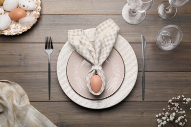 Photo of Festive table setting with bunny ears made of egg and napkin, flat lay. Easter celebration