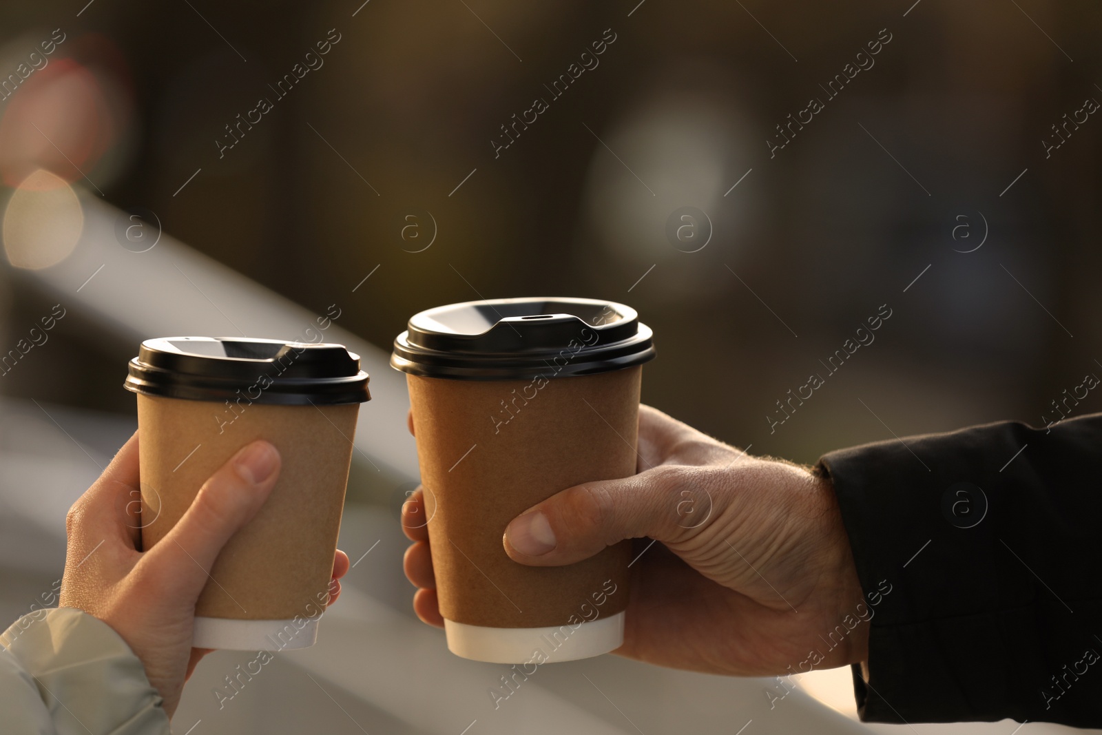 Photo of Couple with takeaway coffee cups outdoors, closeup