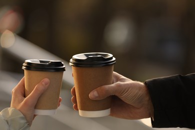 Photo of Couple with takeaway coffee cups outdoors, closeup