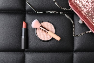 Photo of Makeup products, brush and handbag on black leather background