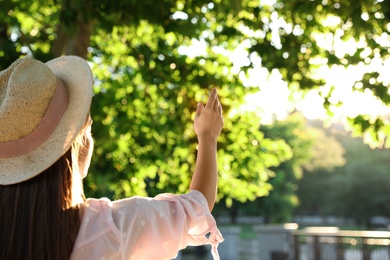 Young woman in hat outdoors on sunny day, back view