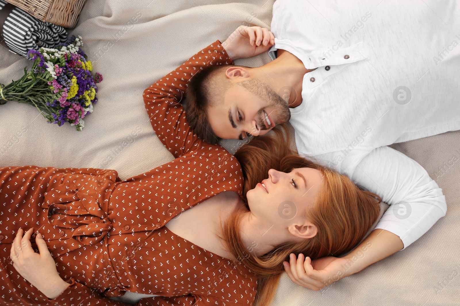 Photo of Happy young couple lying on picnic blanket, above view