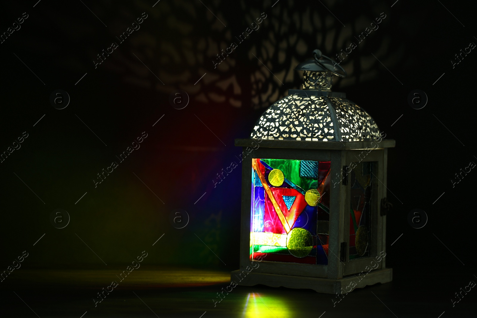 Photo of Decorative Arabic lantern on table against dark background. Space for text