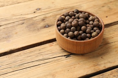 Dry allspice berries (Jamaica pepper)in bowl on wooden table, space for text