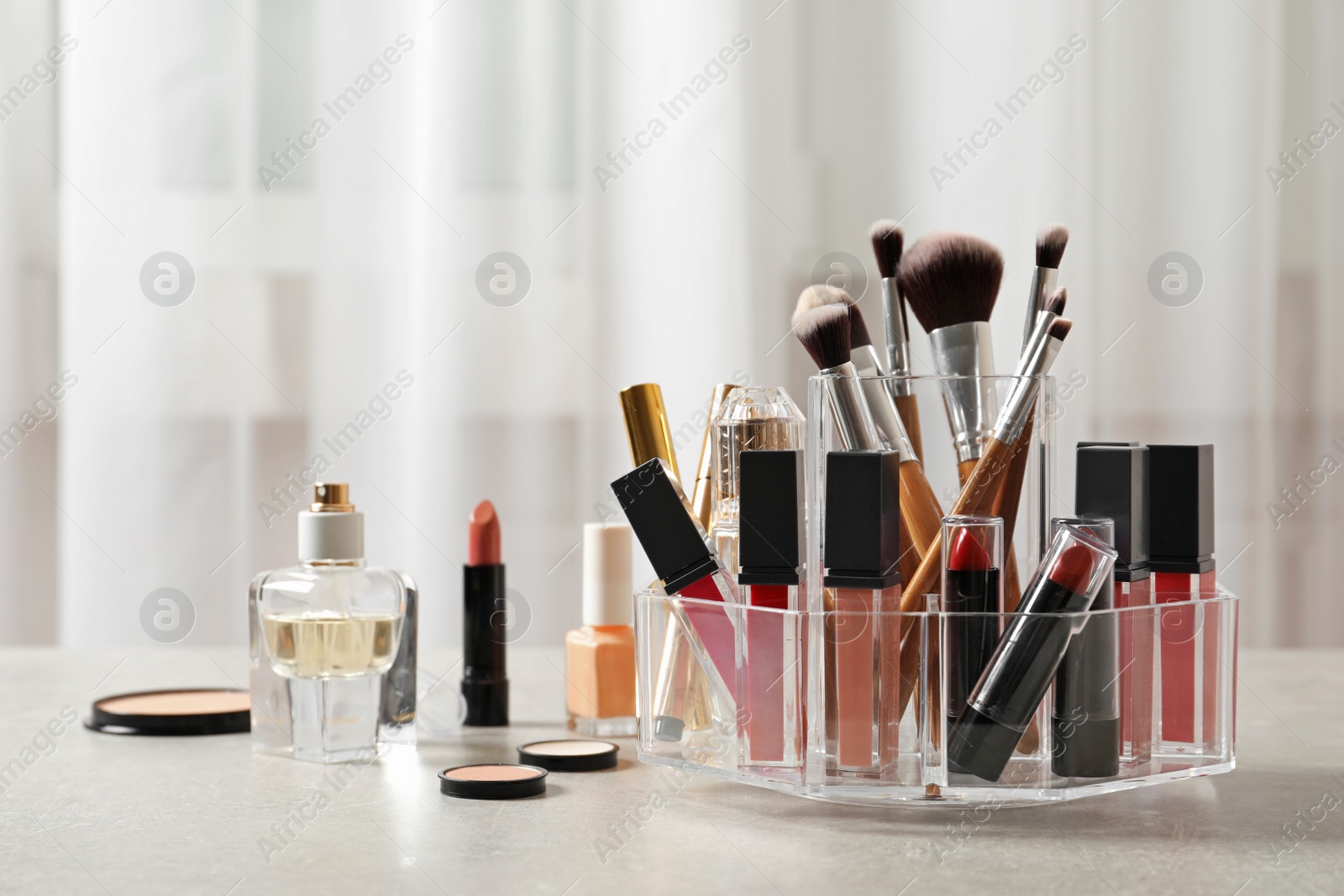 Photo of Lipstick holder with different makeup products on table indoors. Space for text