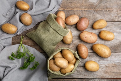 Photo of Flat lay composition with fresh ripe organic potatoes on wooden background