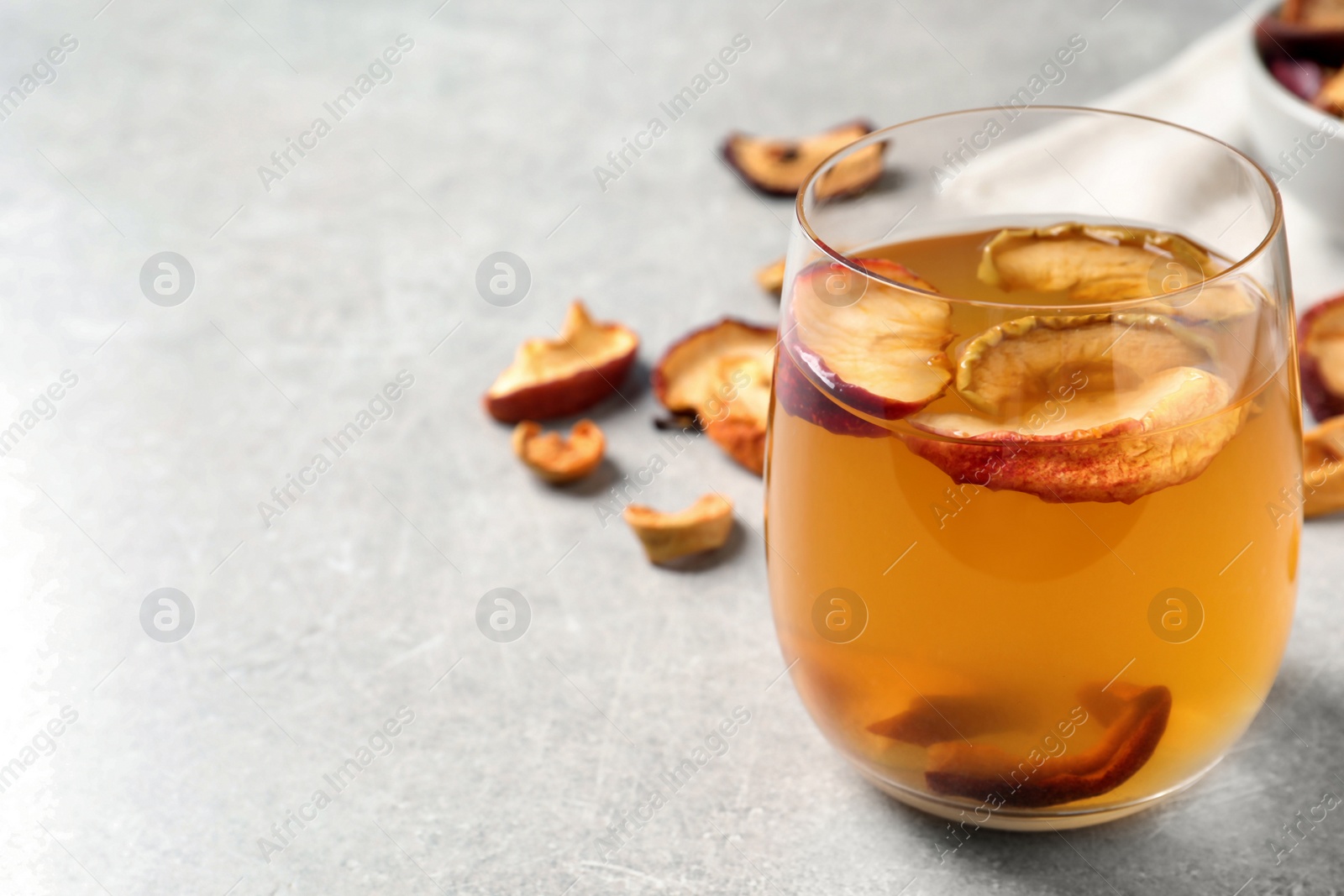 Photo of Delicious compote with dried apple slices in glass on grey table, closeup. Space for text