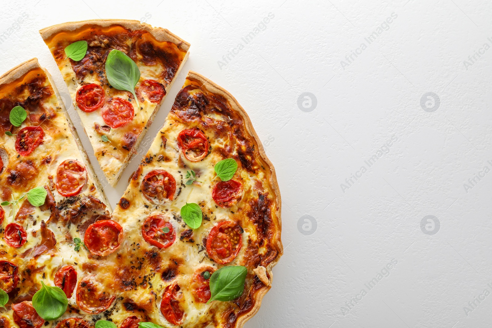 Photo of Cut delicious homemade quiche with prosciutto on white background, top view. Space for text