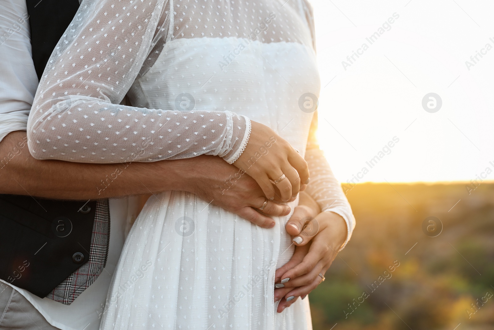 Photo of Happy bride and groom standing outdoors at sunset, closeup