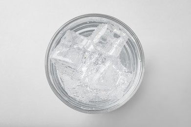 Photo of Glass of soda water with ice on light background, top view