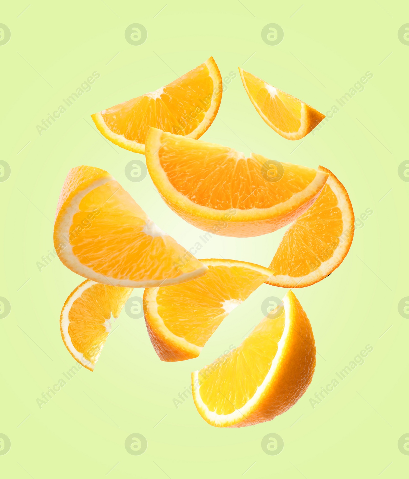 Image of Juicy orange slices flying on pale green background