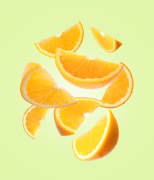 Image of Juicy orange slices flying on pale green background