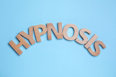 Photo of Word HYPNOSIS made with wooden letters on light blue background, flat lay