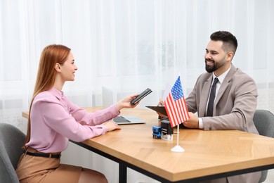 Immigration to United States of America. Woman giving her passport to smiling worker in embassy