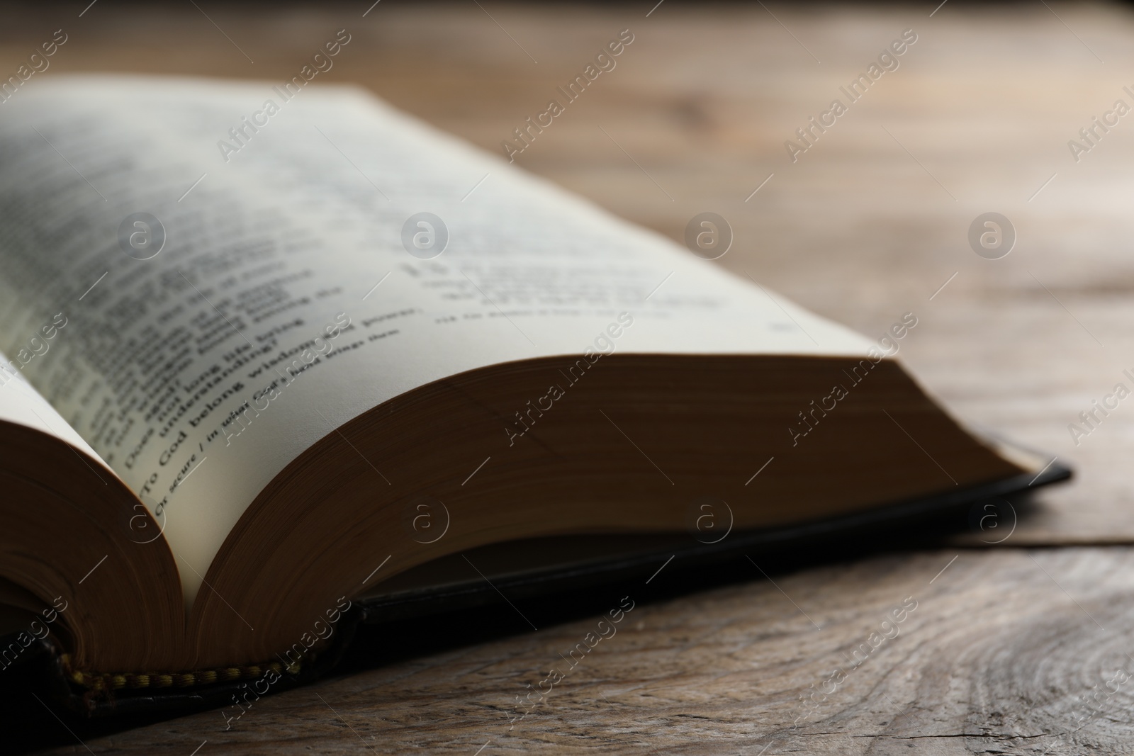Photo of Open Bible on wooden table, closeup. Christian religious book