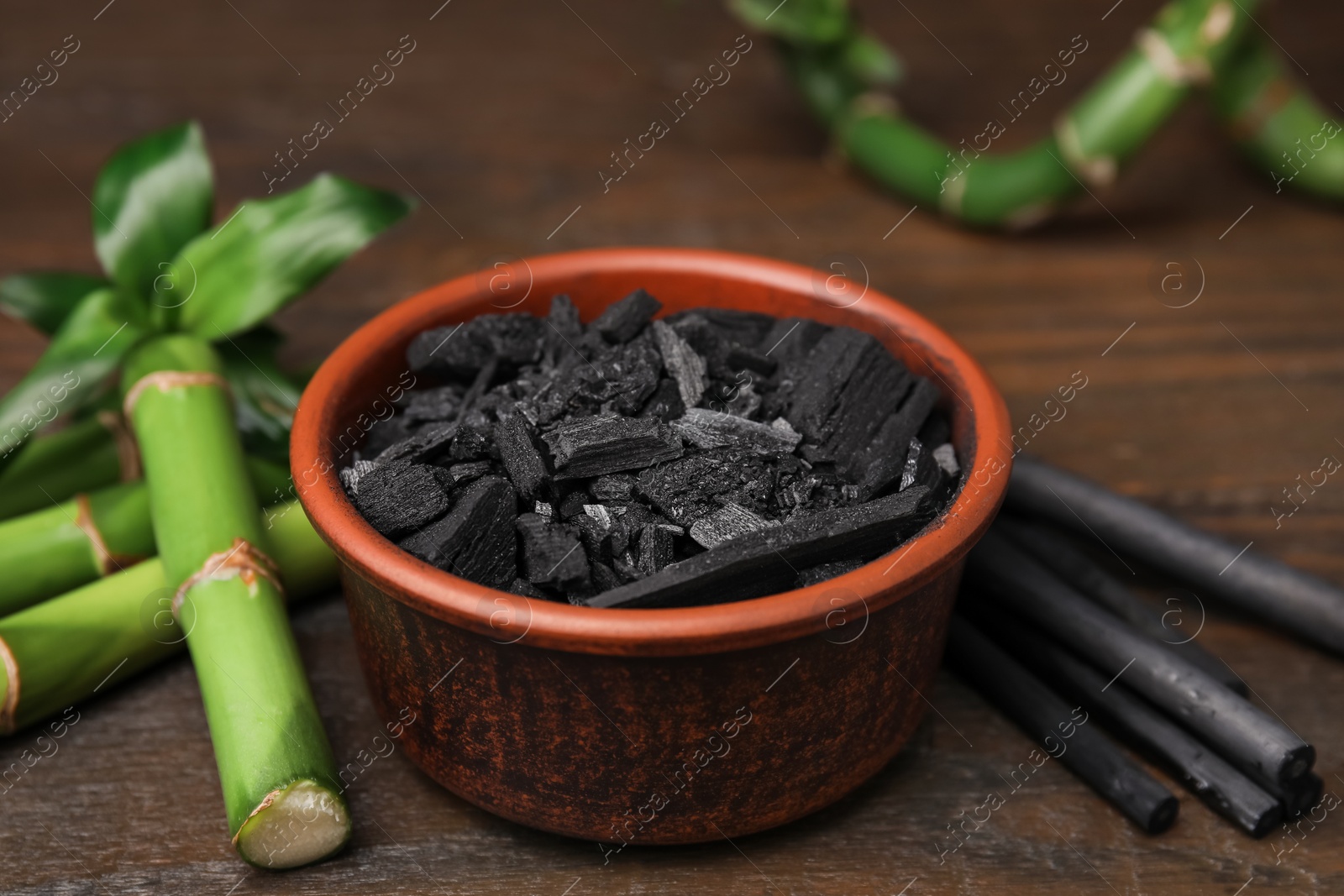 Photo of Fresh bamboo and charcoal on wooden table, closeup
