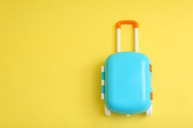 Stylish blue little suitcase on yellow background, top view. Space for text