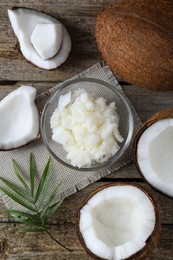 Photo of Organic coconut cooking oil, fresh fruits and leaf on wooden table, flat lay