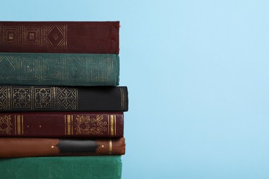 Photo of Stack of old books on light blue background, space for text