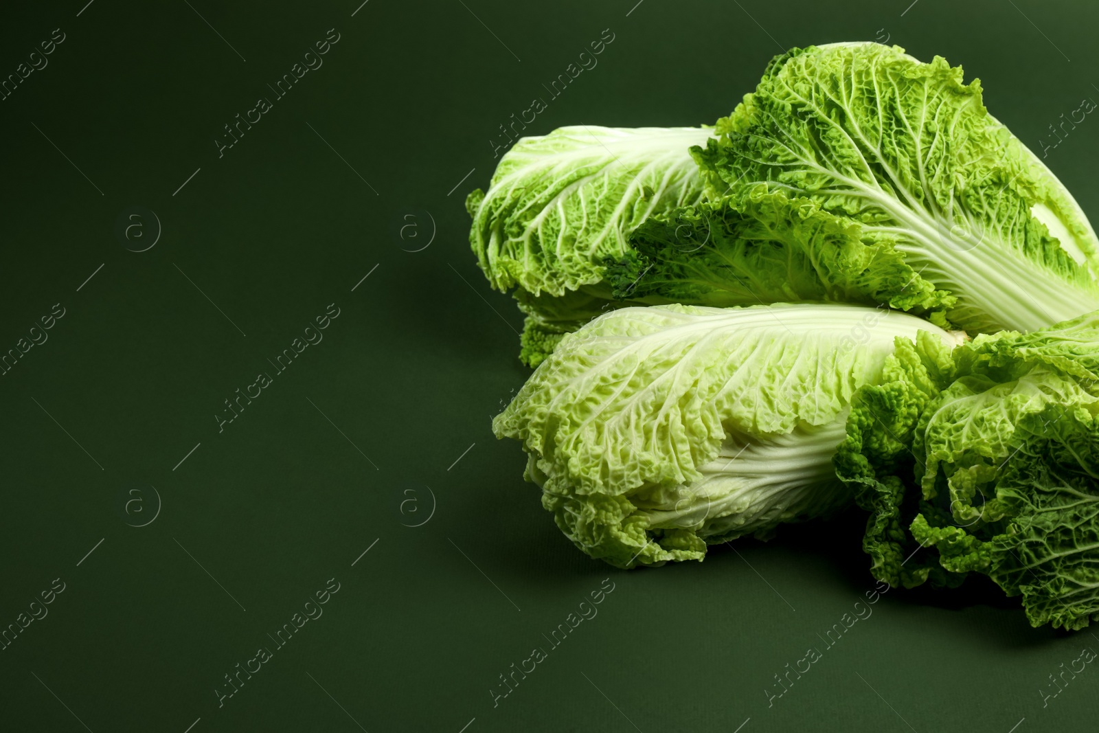 Photo of Fresh ripe Chinese cabbages on green background, space for text