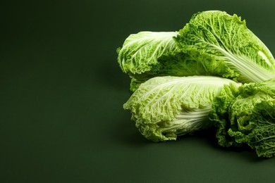 Photo of Fresh ripe Chinese cabbages on green background, space for text