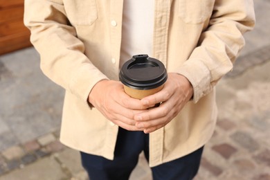 Photo of Coffee to go. Man with paper cup of drink outdoors, closeup