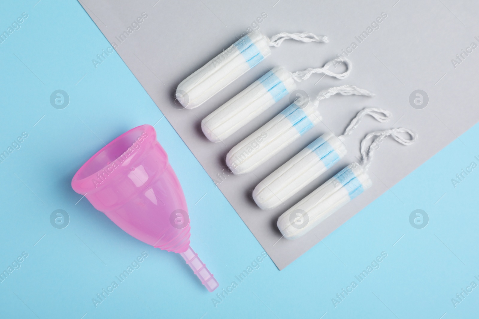 Photo of Menstrual cup and tampons on color background, flat lay