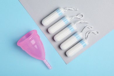 Menstrual cup and tampons on color background, flat lay