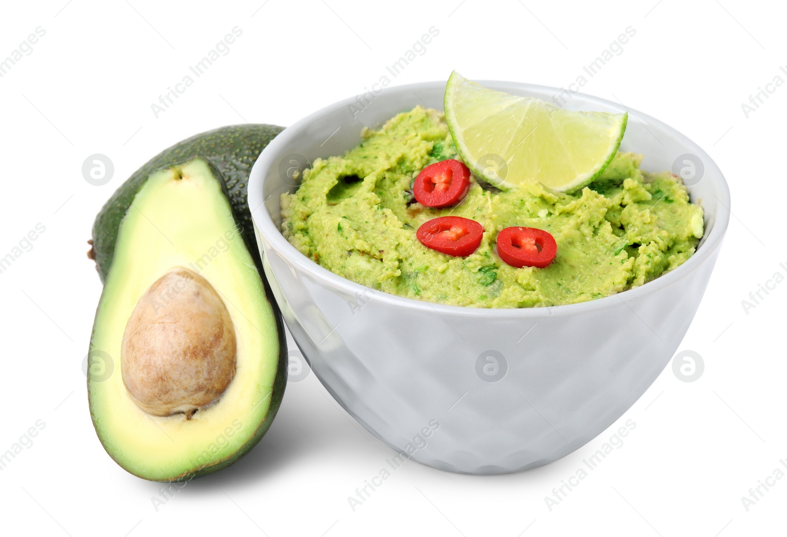 Photo of Bowl of delicious guacamole and fresh avocados isolated on white