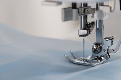Sewing machine with light blue fabric, closeup. Space for text