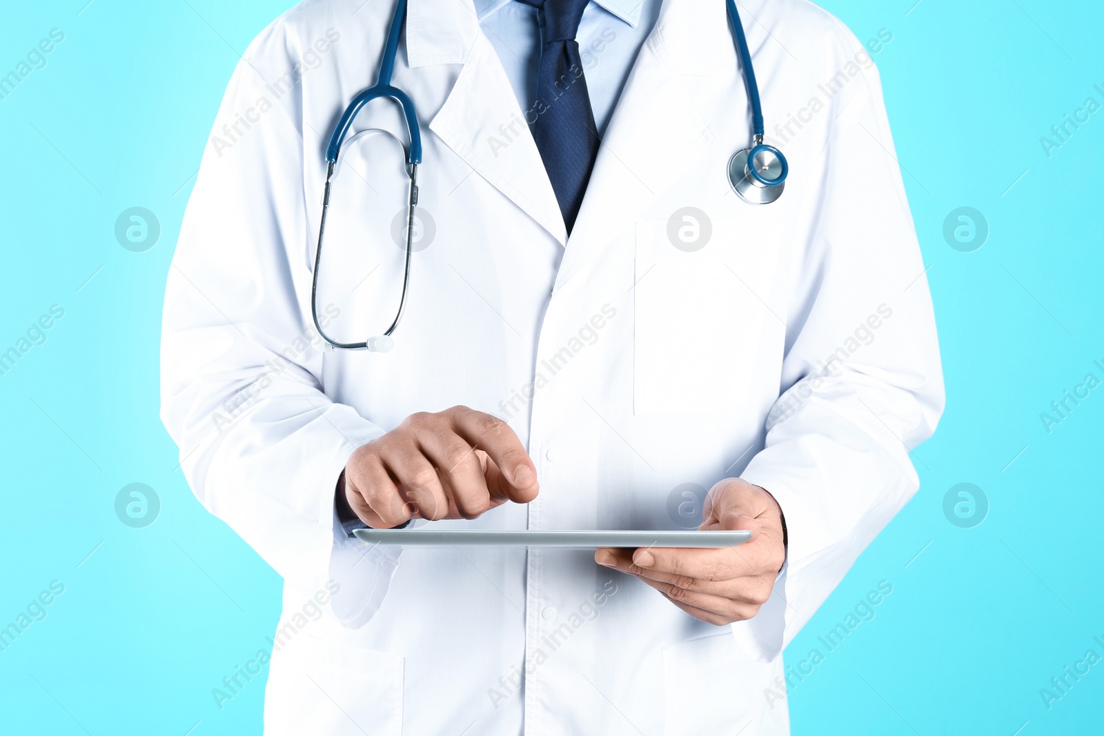 Photo of Male doctor holding modern tablet on color background, closeup