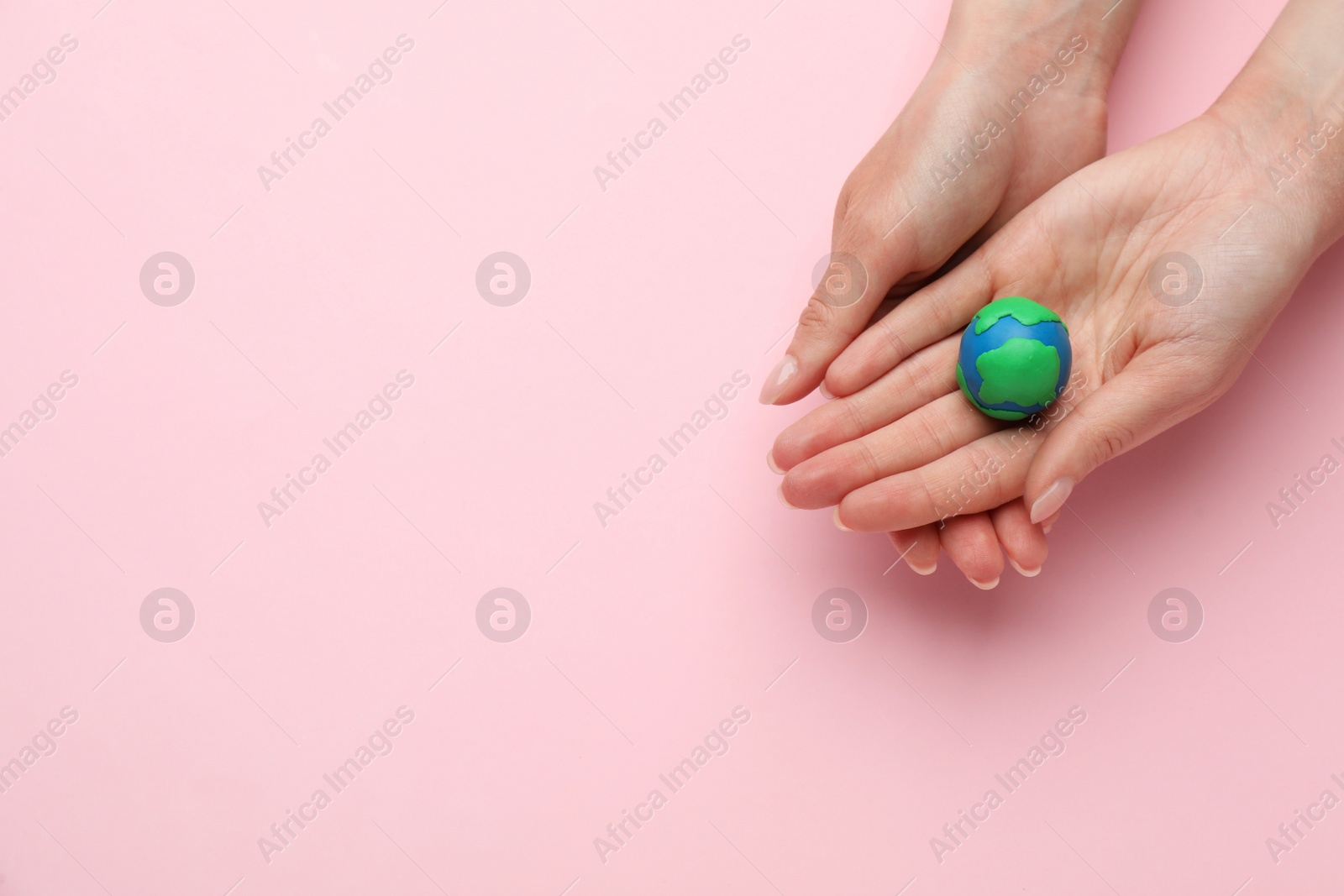 Photo of Woman holding model of planet on pink background, top view with space for text. Earth Day