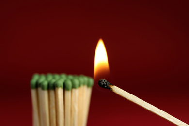 Photo of Burning match near unlit ones on red background