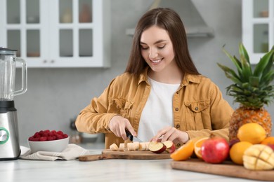 Woman preparing ingredients for tasty smoothie at white marble table in kitchen