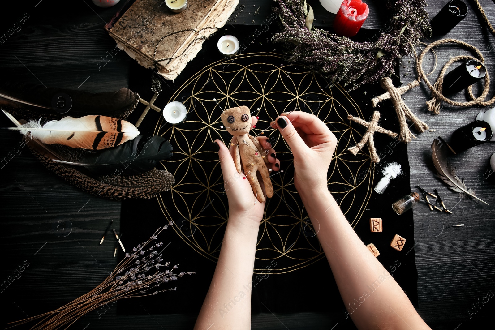 Photo of Woman stabbing voodoo doll with needle at table, closeup. Curse ceremony