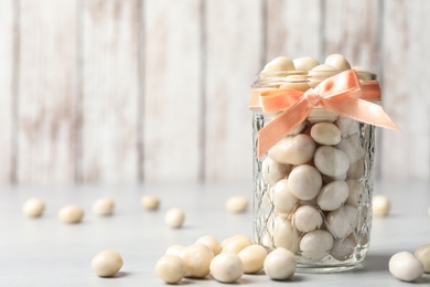 Glass jar with sweets on light grey table. Space for text