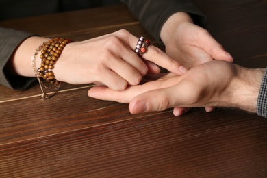 Chiromancer reading lines on man's palm at table, closeup