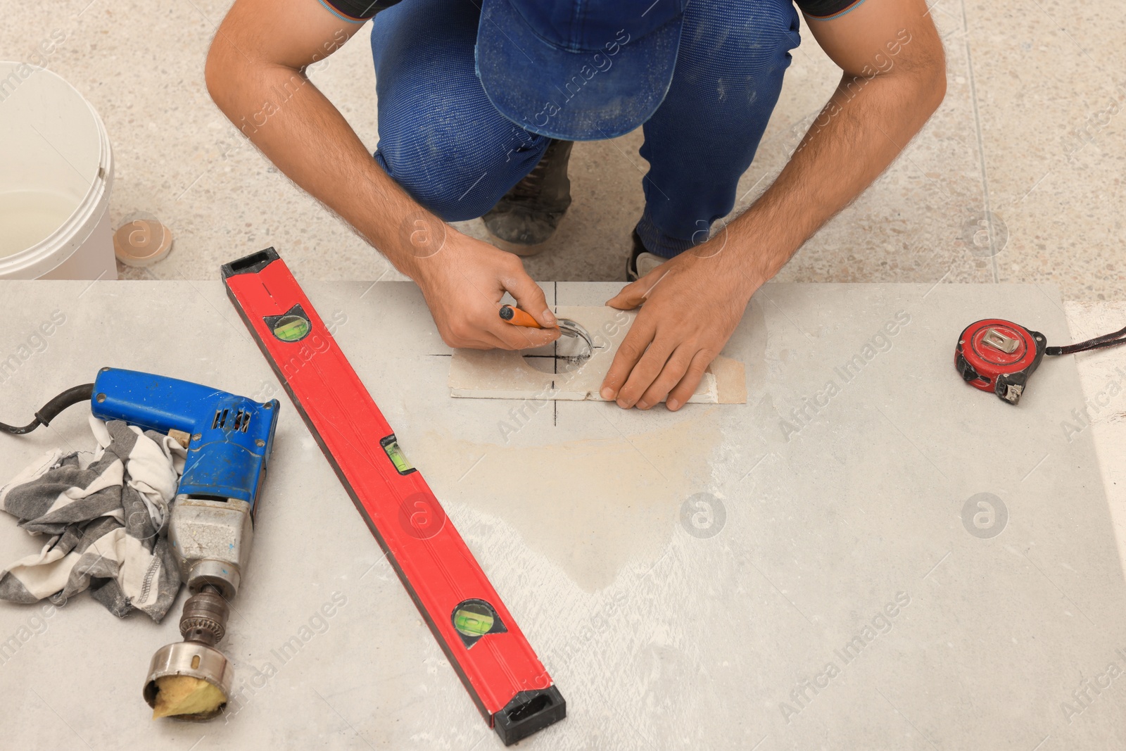 Photo of Worker making socket hole in tile indoors, closeup