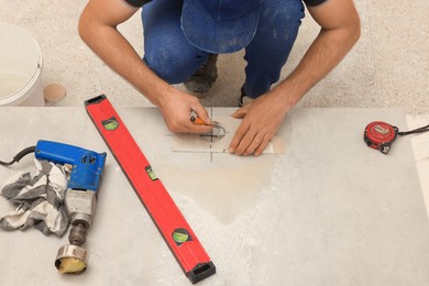 Worker making socket hole in tile indoors, closeup