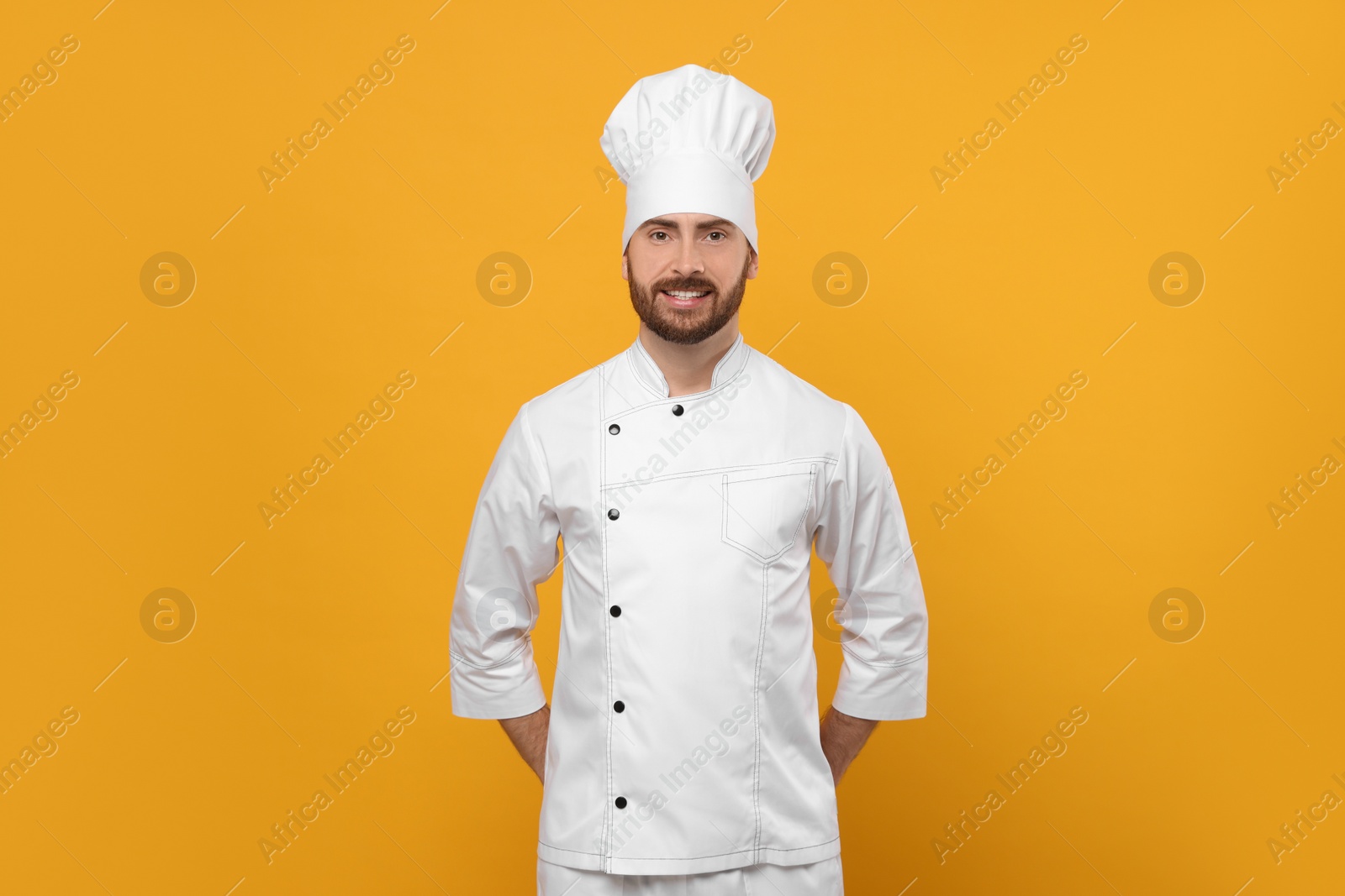 Photo of Smiling mature male chef on orange background