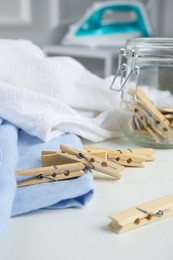 Many wooden clothespins and garments on white table indoors