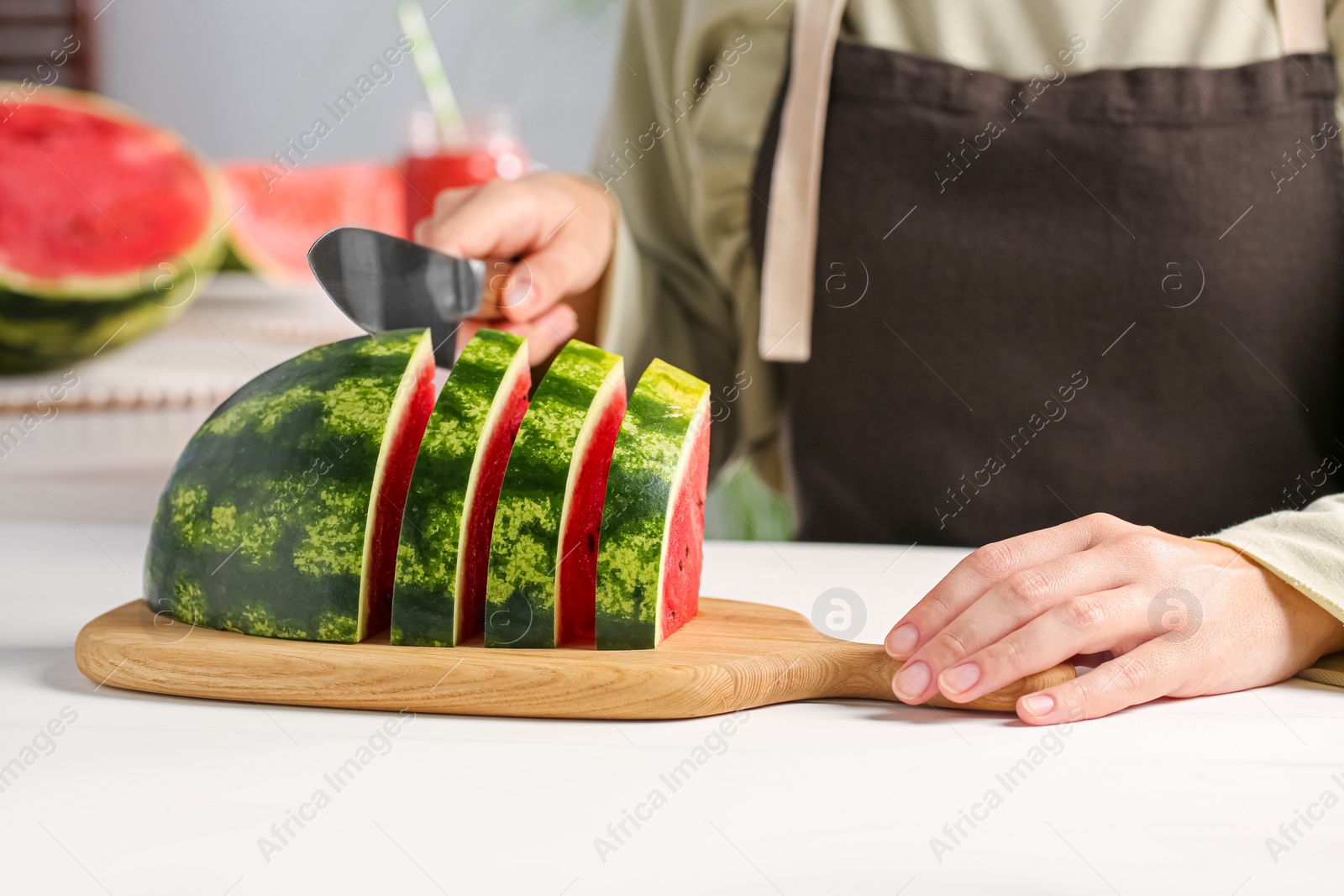 Photo of Woman cutting delicious watermelon at white wooden table indoors, closeup